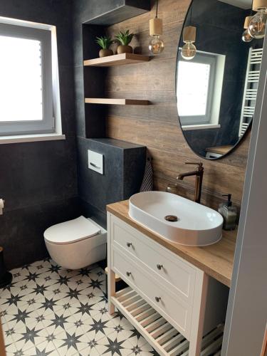 a bathroom with a sink and a toilet and a mirror at Domek Mirage Garden in Trzęsacz