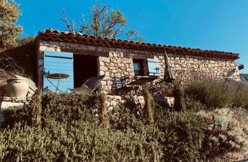 a small stone house with a table in the doorway at La Bergerie du Haut Var in Bargème