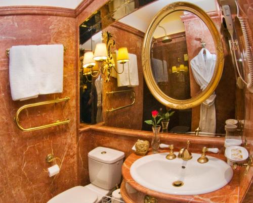 a bathroom with a sink and a mirror and a toilet at Imperial Hotel & Restaurant in Vilnius