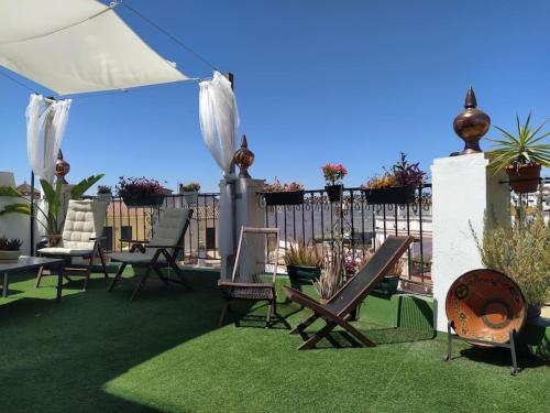 d'une terrasse avec des chaises et un parasol sur la pelouse. dans l'établissement Casa Mora Triana, à Séville
