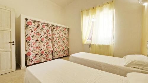una camera con due letti e una finestra con una tenda di Villa Paradiso by Salento Affitti a Marina di Mancaversa