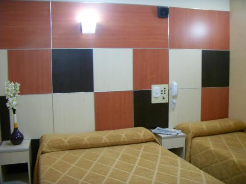 a room with two beds and a wall withcolored at Hotel Micro in Rosario