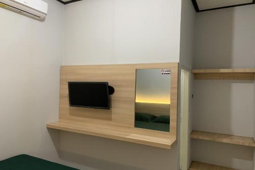 een flatscreen-tv aan een muur in een kamer bij Hotel Merak Indah in Klaten