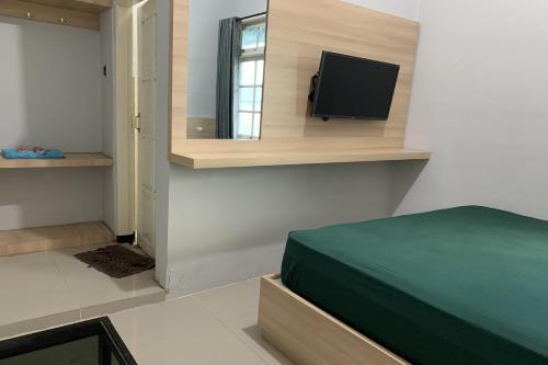 a bedroom with a bed and a flat screen tv at Hotel Merak Indah in Klaten