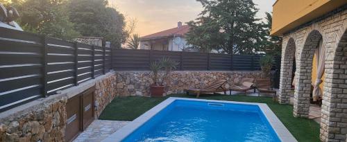 a swimming pool in a yard next to a fence at Holiday house with heated pool Vugica in Polje