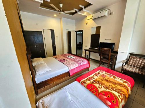 a hotel room with two beds and a table at Suman Cottage & Bungalow in Mahabaleshwar