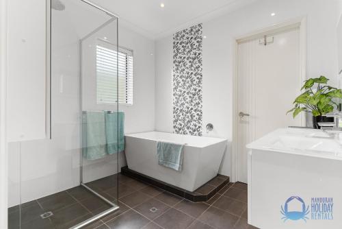 a white bathroom with a tub and a sink at Tuart Heights in San Remo in Mandurah