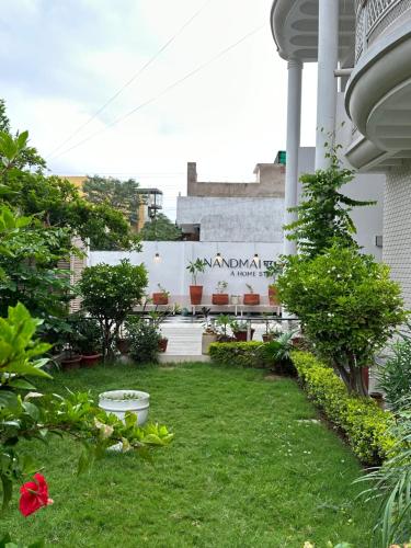 a yard with green grass and a building at AnandMai Ghar - A Homestay in Gwalior in Gwalior