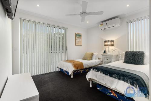 a white room with two beds and a window at Tuart Heights in San Remo in Mandurah