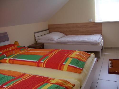 um quarto com 2 camas e cobertores coloridos em LANDHAUS JASMIN ausgezeichnet mit 4 Kristallen - FW Zinkenblick em Bad Mitterndorf