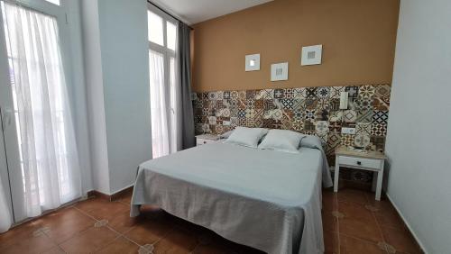 a bedroom with a bed in a room with windows at Hostal Canalejas in Cádiz