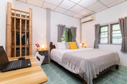 Schlafzimmer mit einem Bett und einem Laptop auf einem Schreibtisch in der Unterkunft Garden Home 1 in Haad Yao