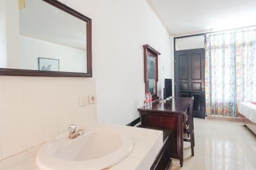 Baño blanco con lavabo y espejo en Hotel Oranjje, en Denpasar