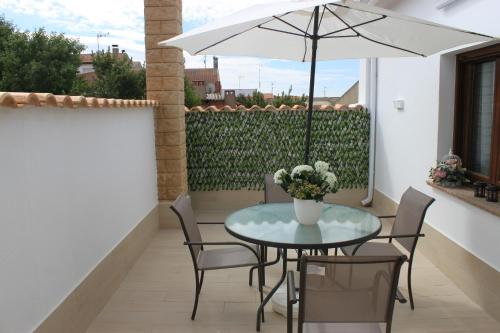 a table and chairs with an umbrella on a balcony at Casa Mirasierra in Mota del Cuervo