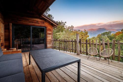 a wooden deck with a table and chairs on a cabin at Pyrénées Prestige - Villas d'exceptions et hébergements insolites in Argelès-Gazost