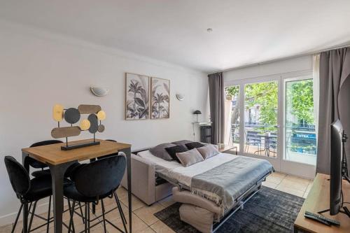 une chambre avec un lit, une table et des chaises dans l'établissement 29 CARNOT - Chaleureux appartement avec balcon - centre ville, à Cannes
