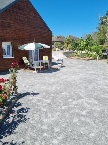a patio with a table and an umbrella next to a building at La Lande Chauvin in La Chapelle-Saint-Aubert