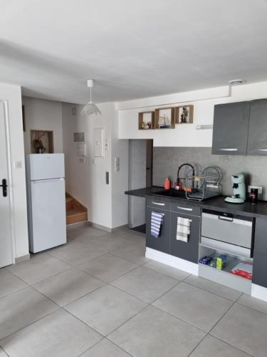 a kitchen with a black counter top and a white refrigerator at La Lande Chauvin in La Chapelle-Saint-Aubert