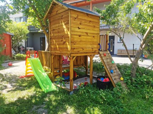 a wooden play house with a ladder and a slide at Domek u Loni in Pobierowo