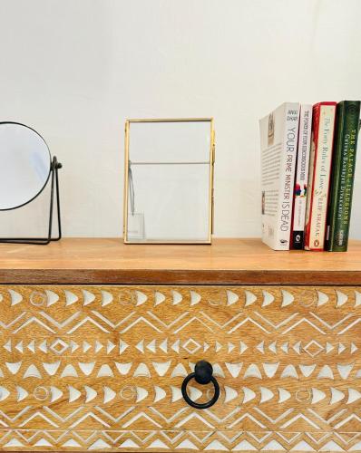 a shelf with books and a mirror on it at AnandMai Ghar - A Homestay in Gwalior in Gwalior