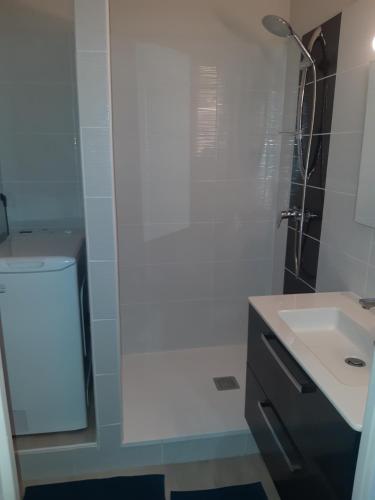 une salle de bain blanche avec une douche et un lavabo dans l'établissement T2 Rez-de-jardin, terrasse et parking, proche de la plage, à La Grande Motte