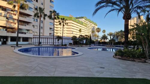 two pools in a courtyard with palm trees and buildings at Apartamento en Calpe, edf. Coral Beach in Calpe