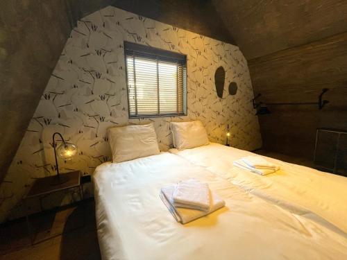 een slaapkamer met een groot wit bed op een zolder bij Loft Heerehof in Schoorl
