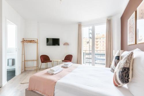 une chambre blanche avec un grand lit et une table dans l'établissement Studio lumineux Paris Est - Serurier, à Paris