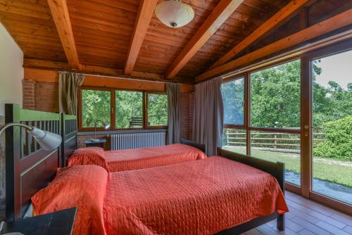 two beds in a room with windows at Casa Rustica singola con piscina immersa nella natura in parco privato in Castel del Piano