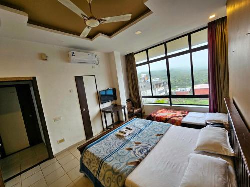a hotel room with two beds and a large window at Suman Cottage & Bungalow in Mahabaleshwar