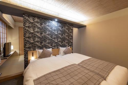 a bedroom with a large bed and a wall at Oyado Kyoto Shinmachi in Kyoto
