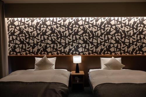 two beds in a hotel room with a large wall at Oyado Kyoto Shinmachi in Kyoto