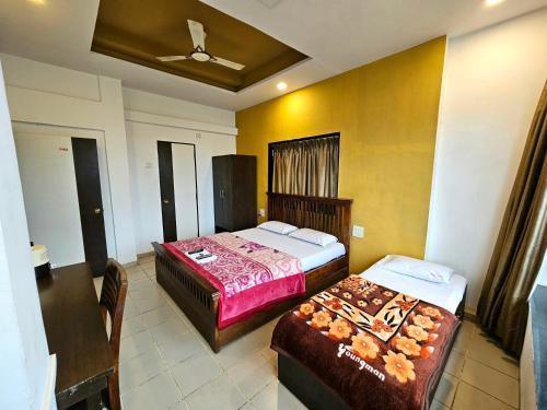 a hotel room with two beds and a table at Suman Cottage & Bungalow in Mahabaleshwar