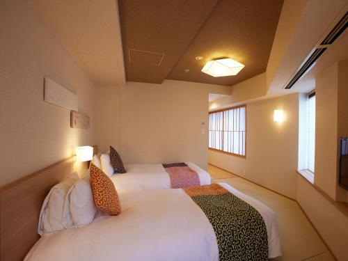 two beds in a room with two windows at Kyoto Hot Spring Hatoya Zuihokaku Hotel in Kyoto