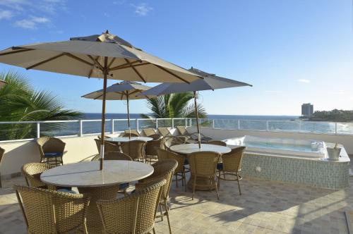a patio with tables and chairs with a view of the ocean at Rede Andrade Express in Salvador