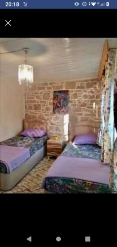 a bedroom with two beds and a stone wall at Ayvalık Rum evi in Ayvalık