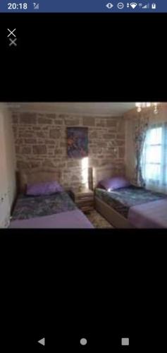 1 dormitorio con 2 camas y pared de ladrillo en Ayvalık Rum evi, en Ayvalık