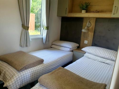three beds in a small room with a window at Cheviot Pines Hot tub in Swarland