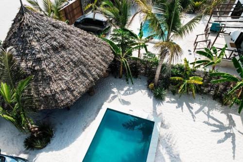 an overhead view of a resort with a swimming pool and a thatch roof at Sand Beach Boutique Villas in Bwejuu
