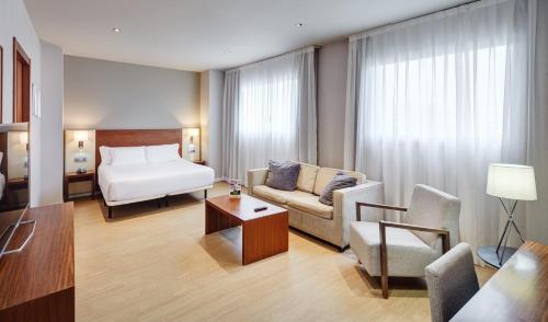 pokój hotelowy z łóżkiem i kanapą w obiekcie Sercotel Ciutat de Montcada w mieście Montcada i Reixac
