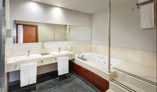 a bathroom with two sinks and a tub and a mirror at Sercotel Ciutat de Montcada in Montcada i Reixac