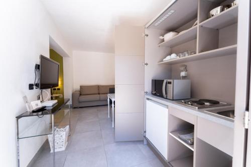 a small kitchen with white cabinets and a microwave at Villa Mosca Charming House in Alghero