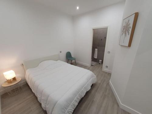 a white bedroom with a white bed and a chair at Roquebrune : Appartement 4 personnes proche de la plage (AV) in Roquebrune-Cap-Martin