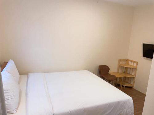 a bedroom with a white bed and a chair at Hung Vuong Hotel in Pleiku