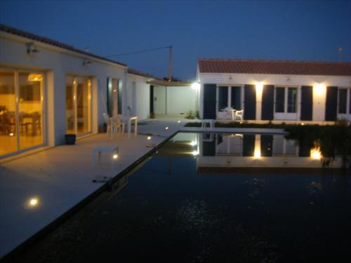 une piscine devant une maison la nuit dans l'établissement Les Mouettes, à La Cotinière