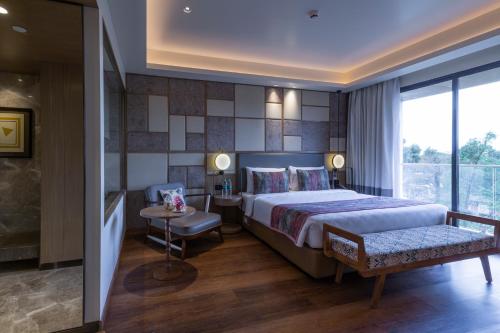 a bedroom with a king sized bed and a window at Regenta SGS Greenotel - Lonavala in Lonavala