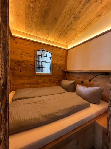 a bed in a wooden room with a window at BERGLAGE - Das UrlaubZuhause - Ferienhäuser in Braunlage