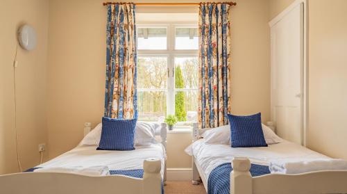 two beds in a room with a window at Bibby Lot in Rusland