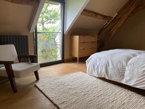 ein Schlafzimmer mit einem Bett, einem Stuhl und einem Fenster in der Unterkunft La Ferme de Châtenoy - Le Mouton Noir in Châtenoy