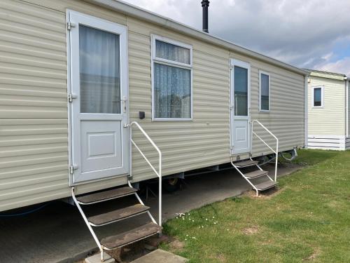 a mobile home with two doors and two stairs at Luxury 8 and 6 berth caravans in Jaywick Sands